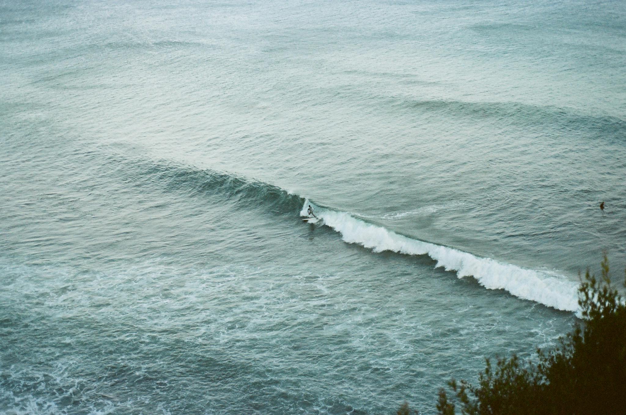 A lone surfer rides gentle waves on a serene day at sea, capturing the essence of ocean adventure.