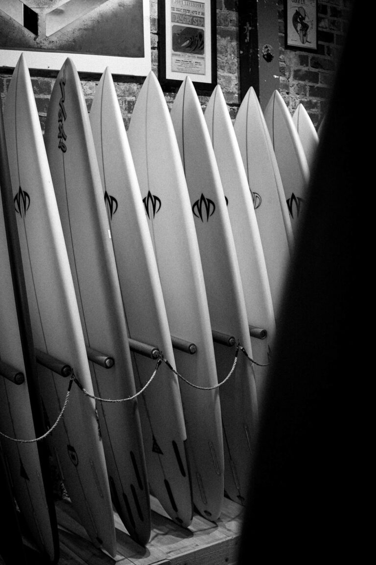 Row of surfboards displayed in a surf shop, creating a striking black and white composition.